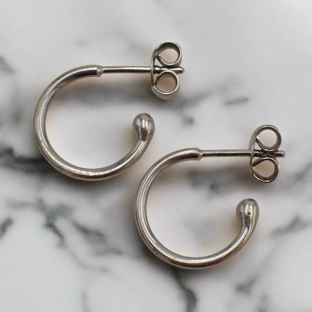 White gold loop stud earrings rest on a white surface.