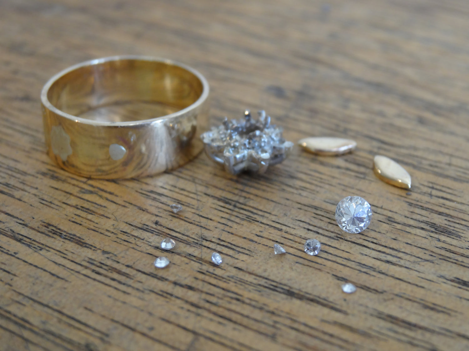 A dismantled ring on a wooden worktop with loose stones laying in foreground 