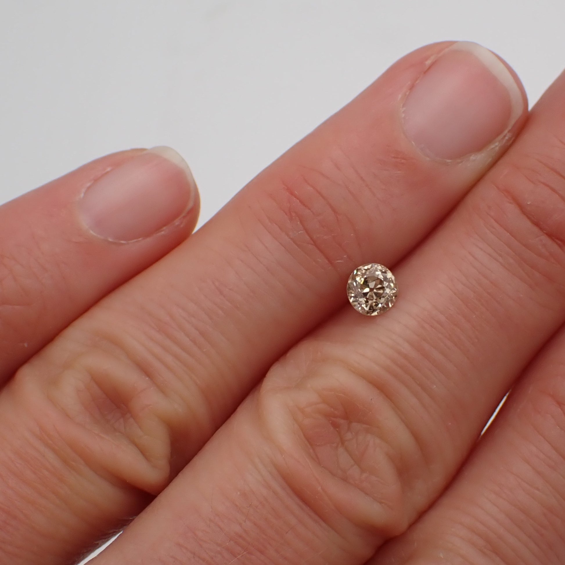 a champange, antique diamond rests between two fingers