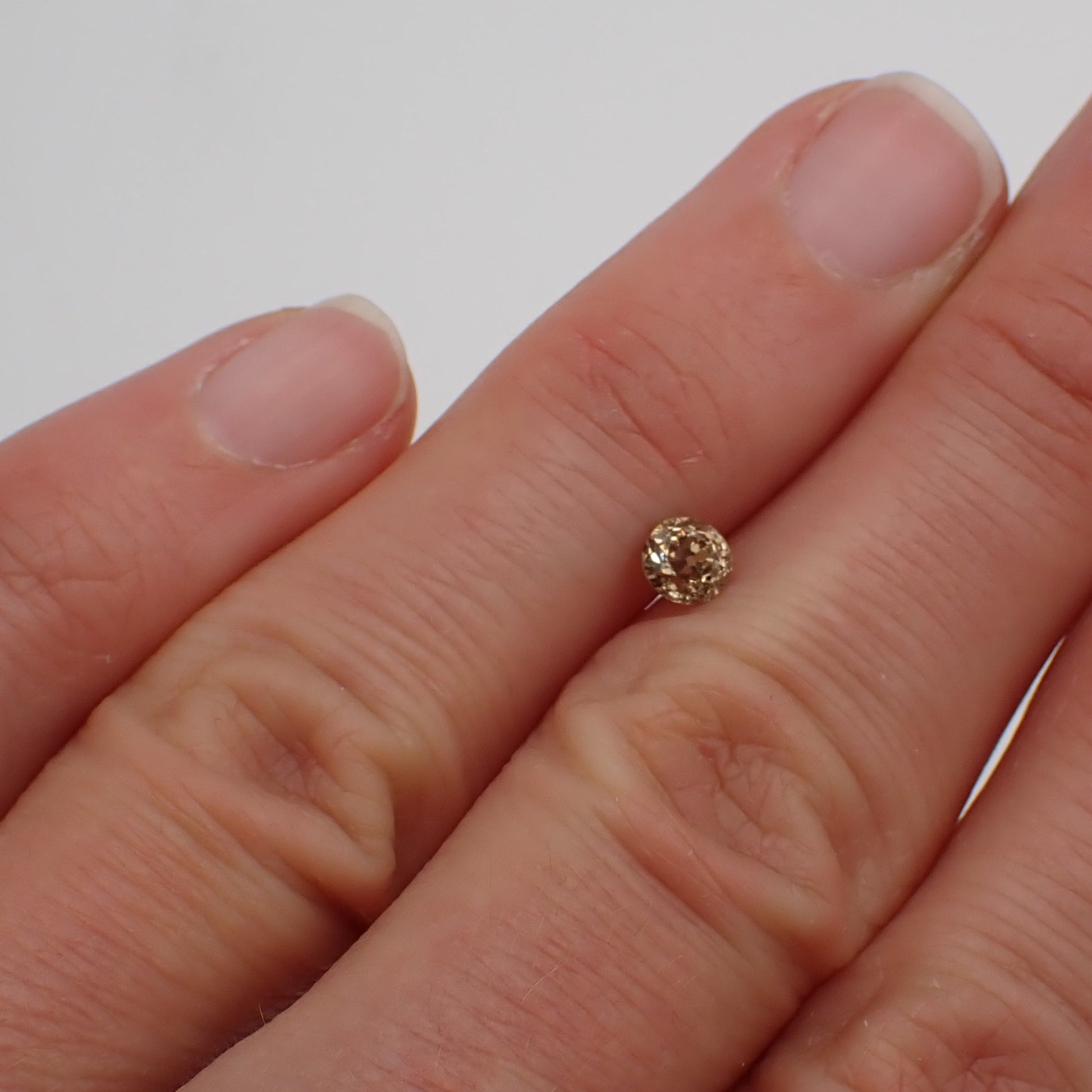 an antique champagne diamond rests between two fingers