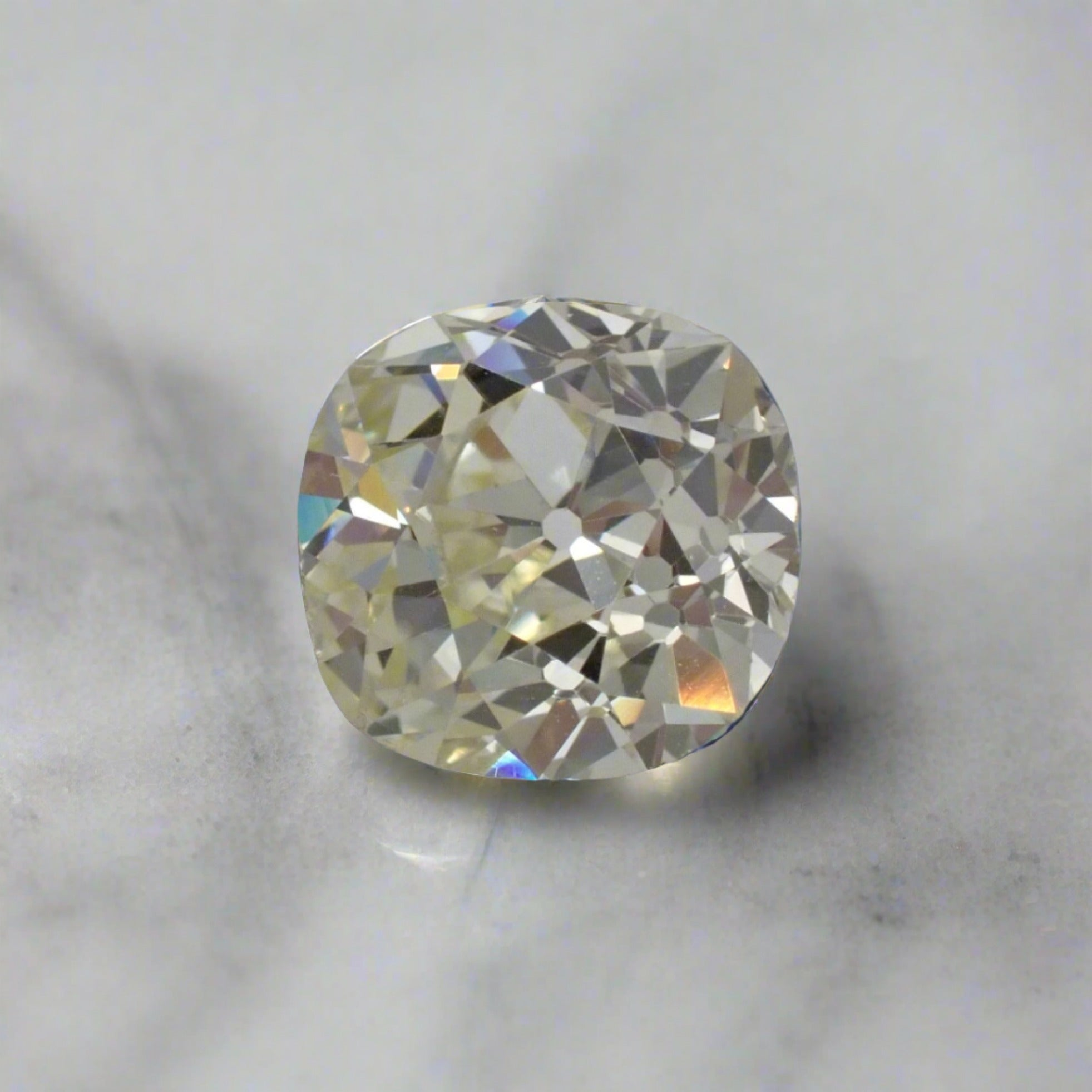 A tinted, cushion shaped antique diamond clearly shows the irregular, hand cut facets.