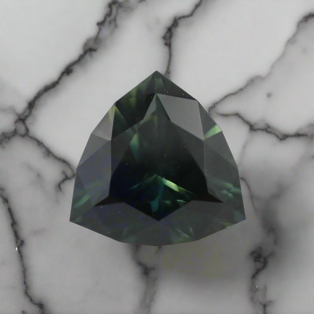 Faceted green gemstone on a light gray background