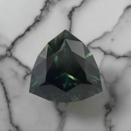 Faceted green gemstone on a light gray background