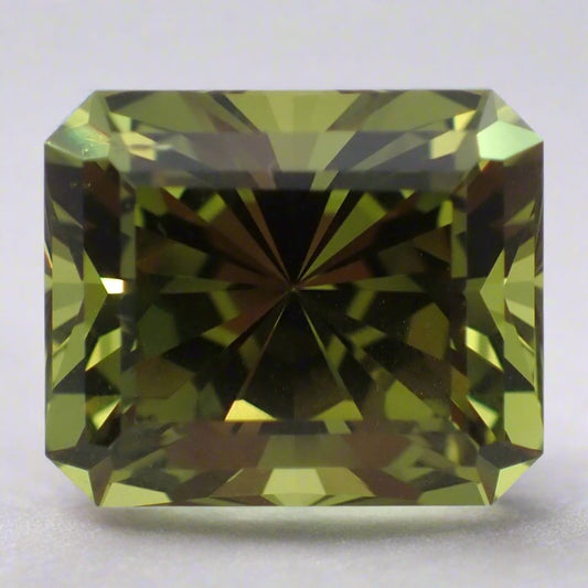 A large green sapphire rests on a white surface. It is rectangular with the corners cut off.