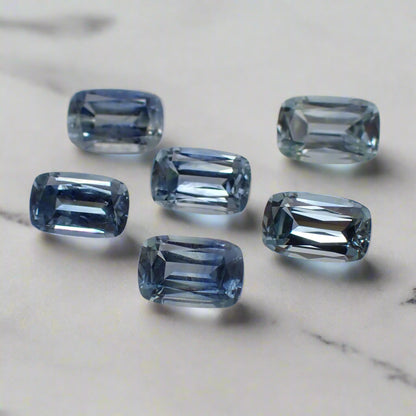 a set of six light blue sapphires rest on a white marble surface