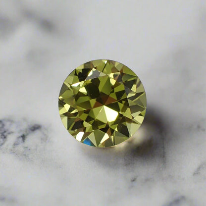 A round yellow sapphire, loose, against a white marble background