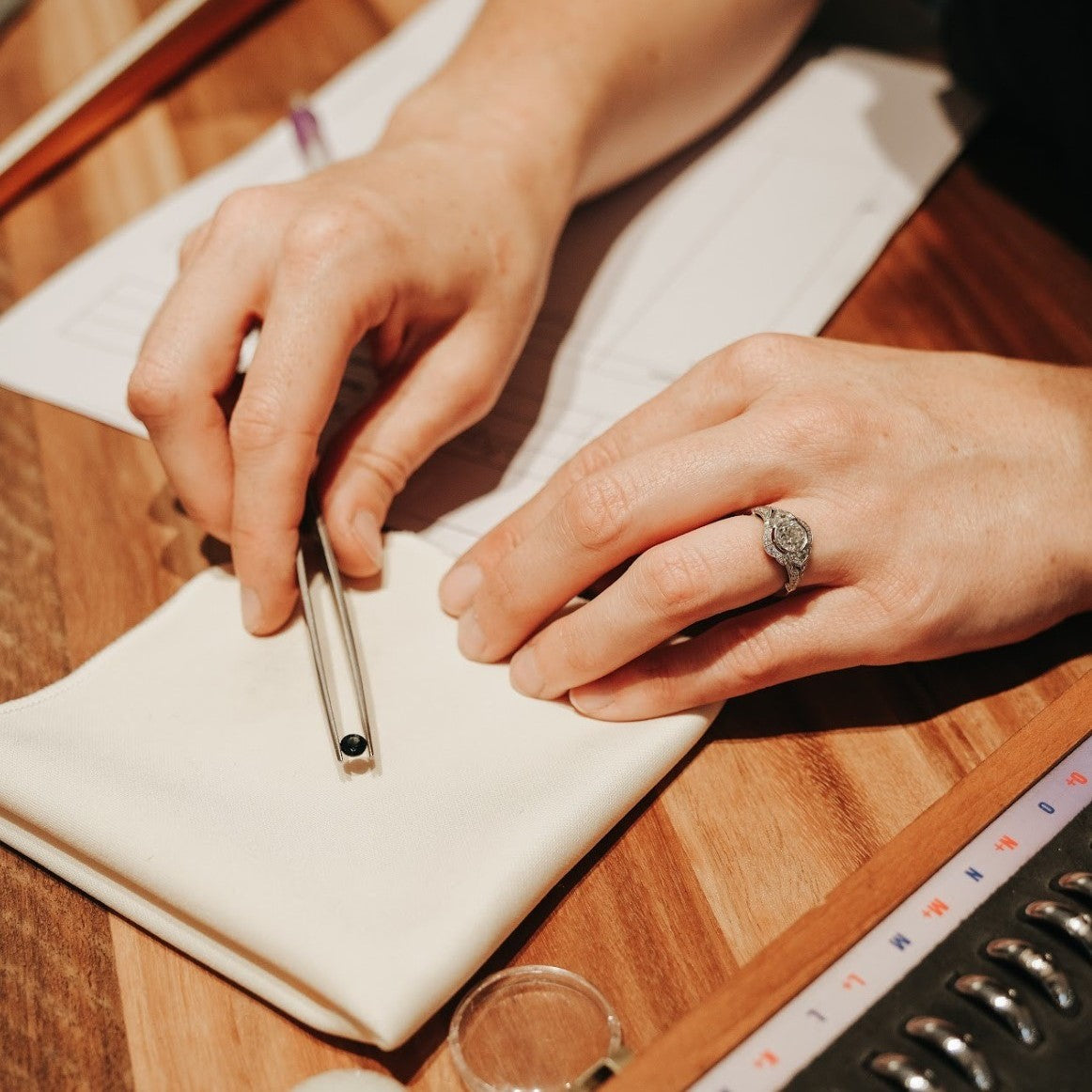 A jeweller holds a loose sapphire in a pair of tweezers as part of the custom design process.