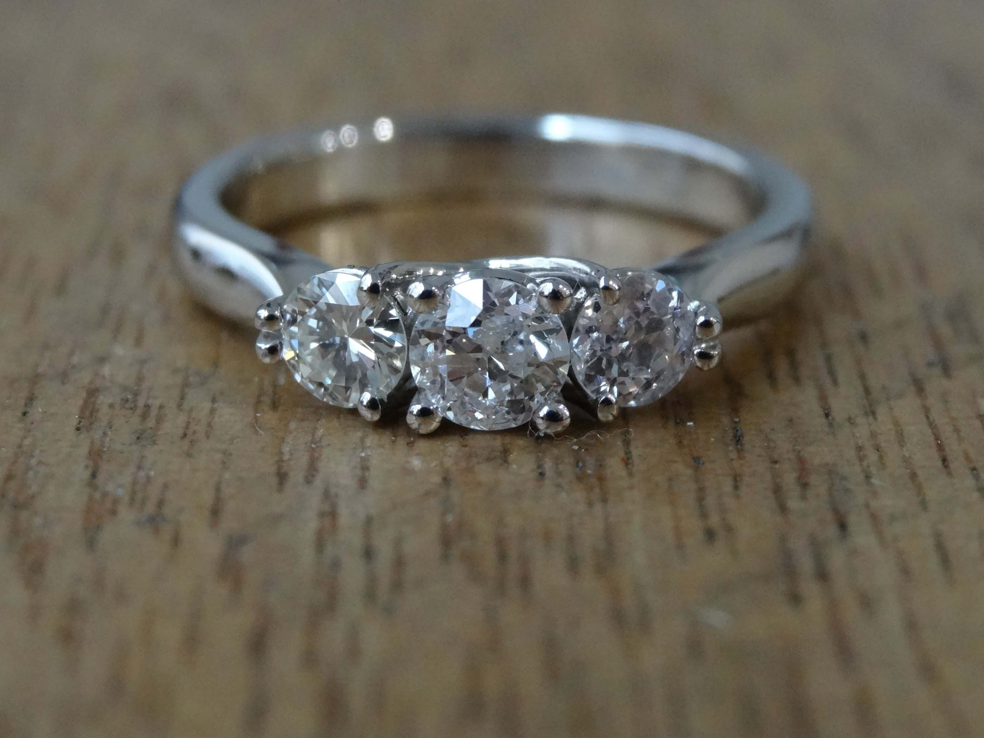 Platinum engagement ring set with three antique diamonds in claw settings.