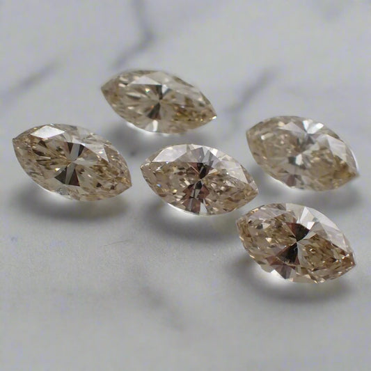 a set of five champagne, marquise cut diamonds, loose and resting on a white surface