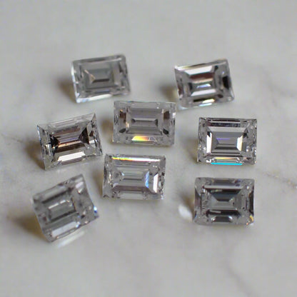 A set of eight small baguette cut diamonds rests on a white surface.