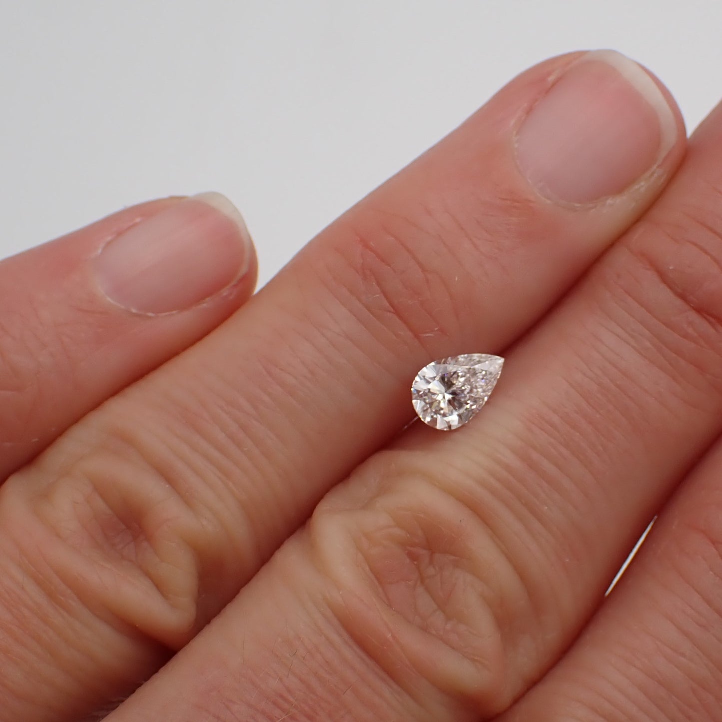 a recycled pear cut diamond rests between two fingers