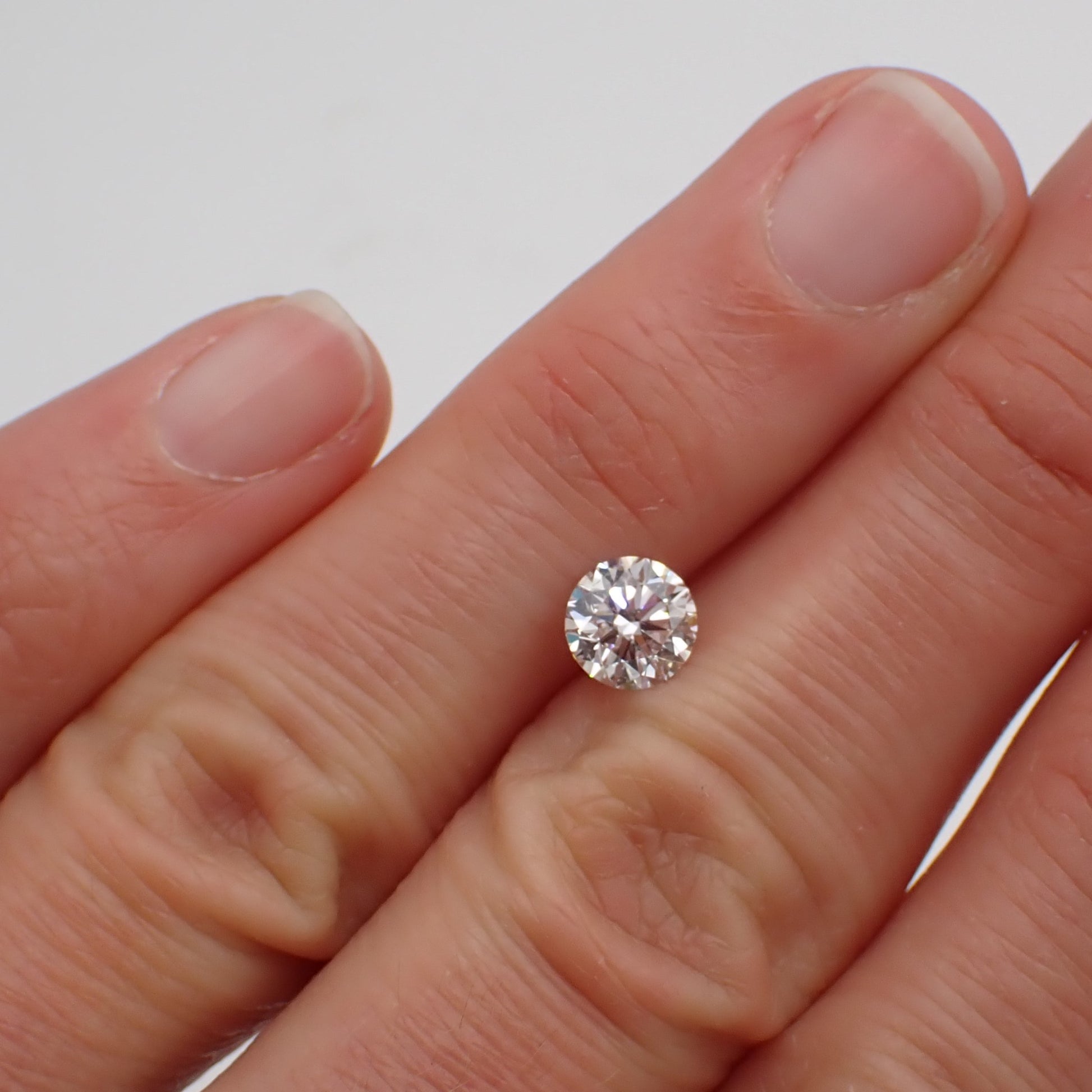 a recycled 90 point round white diamond rests between two fingers