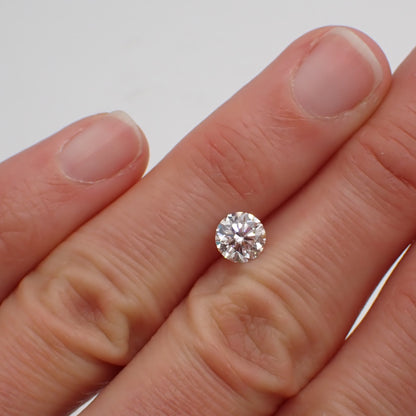 a recycled 90 point round white diamond rests between two fingers