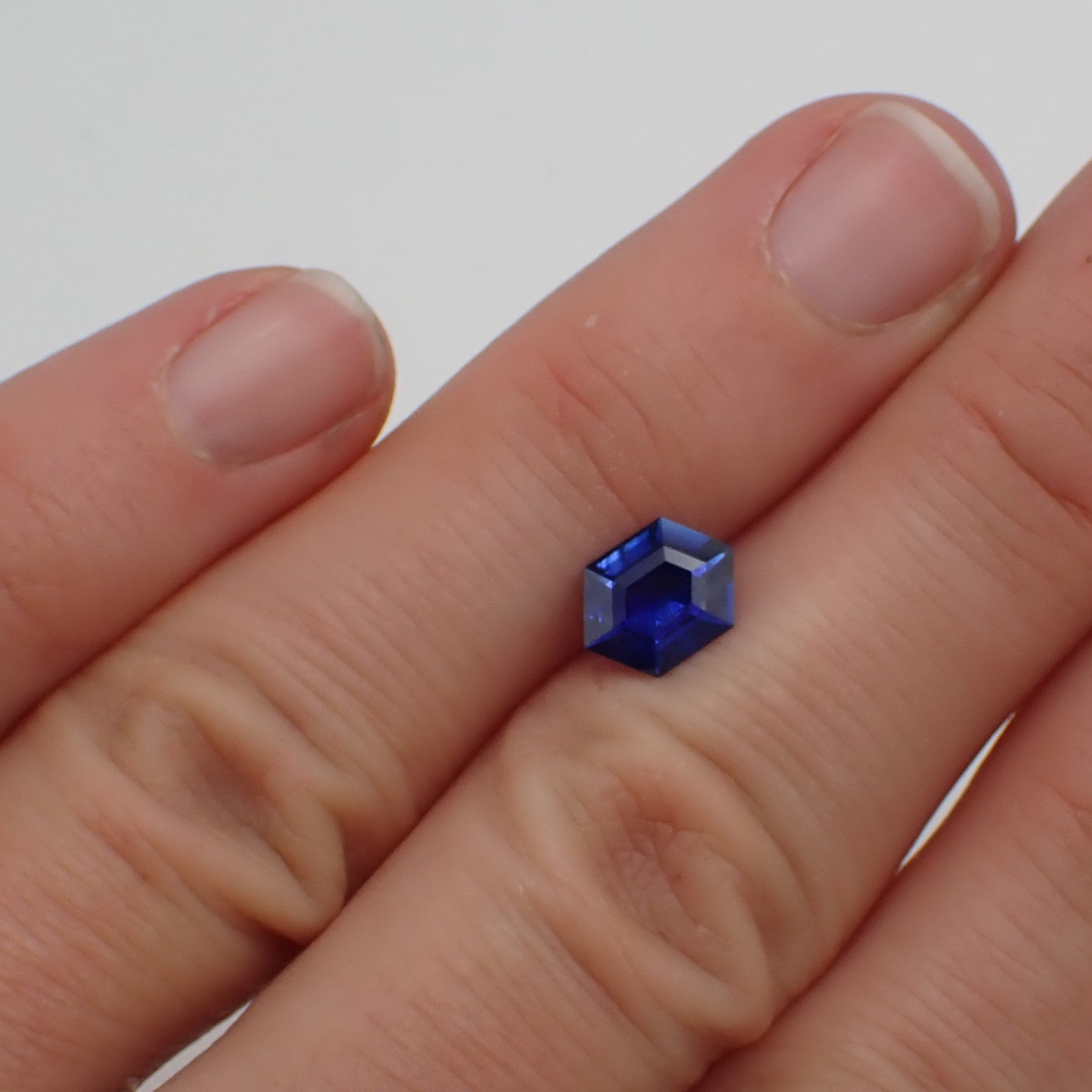 a rich, bright blue sapphire rests between two fingers.