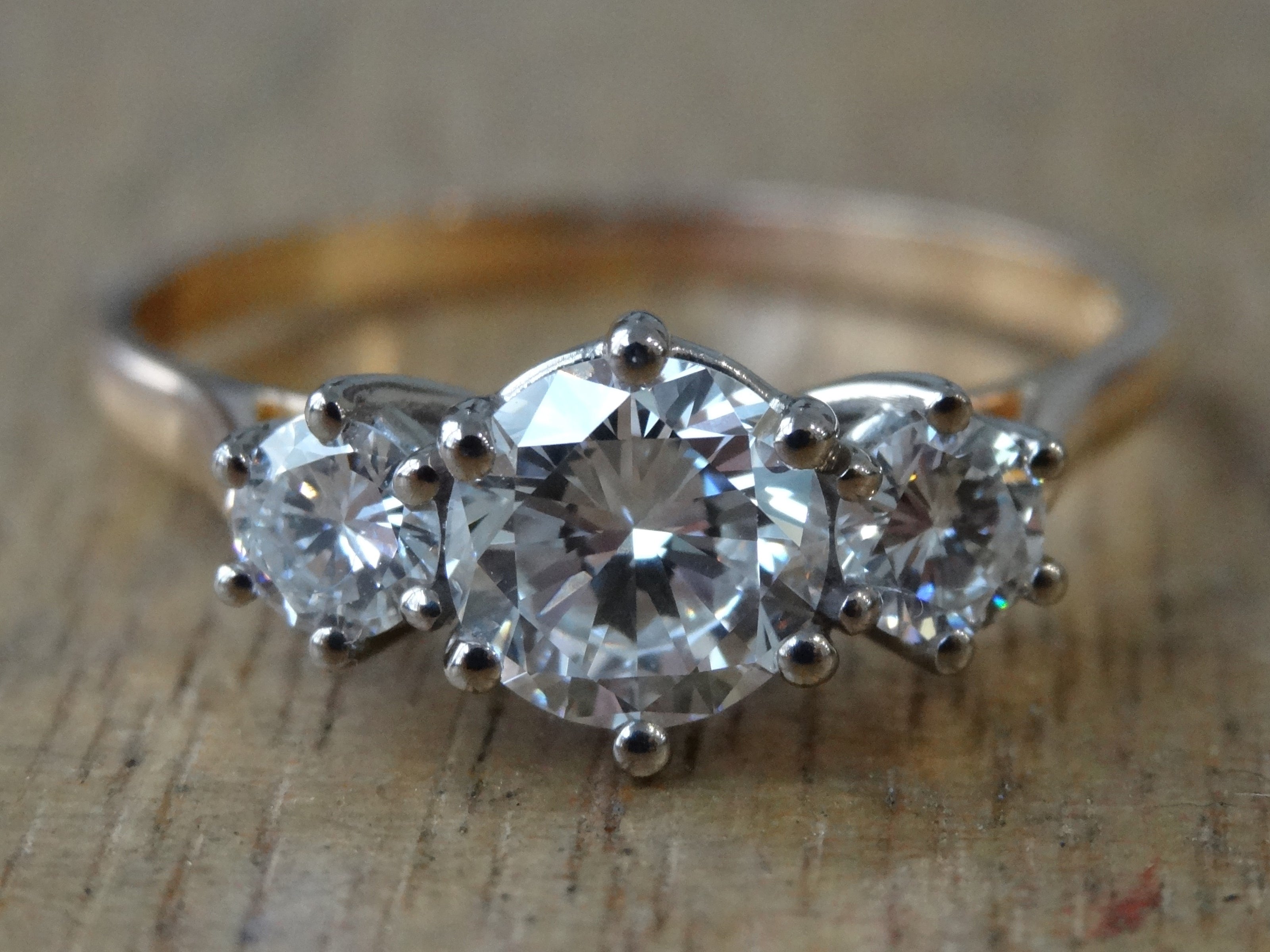 A claw set diamond engagement ring with three round stones in an antique style.