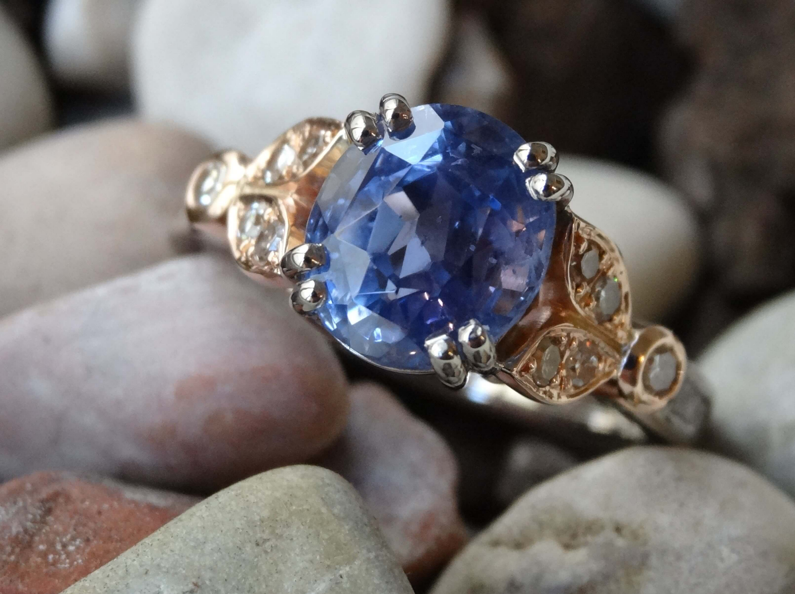 A re-cut sapphire is double claw set in white gold with rose gold and diamond shoulders.