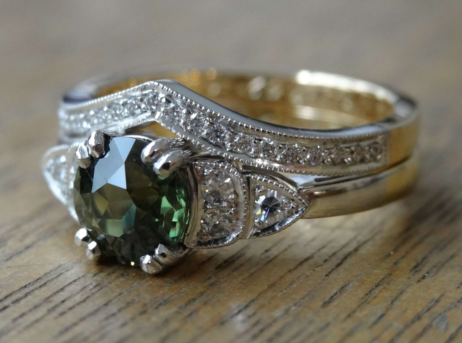 An antique, green sapphire set in an art deco inspired engagement ring with a fitted wedding ring.